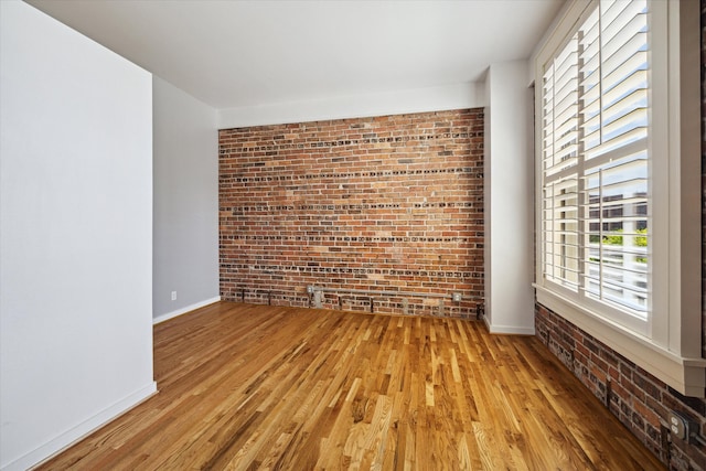 empty room featuring light hardwood / wood-style flooring and brick wall