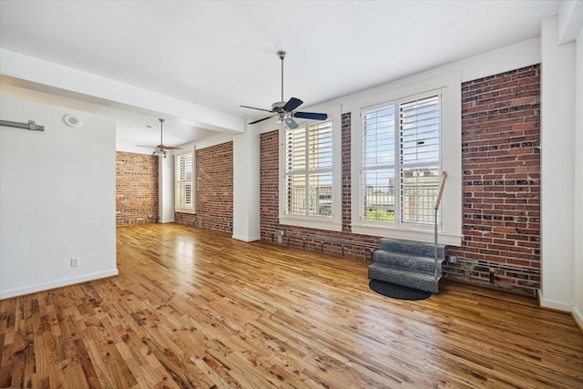 unfurnished living room with light hardwood / wood-style flooring and brick wall