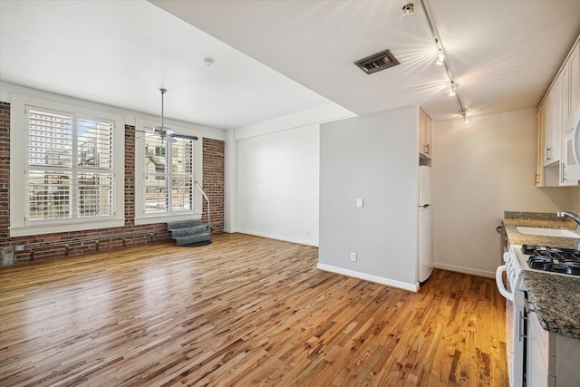 unfurnished dining area with light hardwood / wood-style flooring, ceiling fan, track lighting, and sink