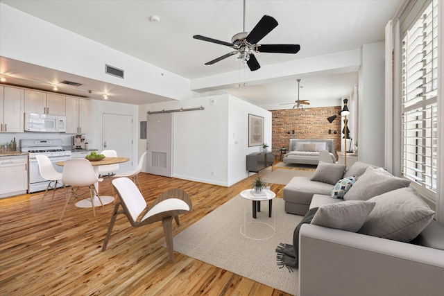 living room with ceiling fan, light hardwood / wood-style flooring, and a barn door