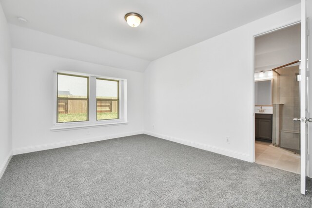 carpeted empty room featuring lofted ceiling