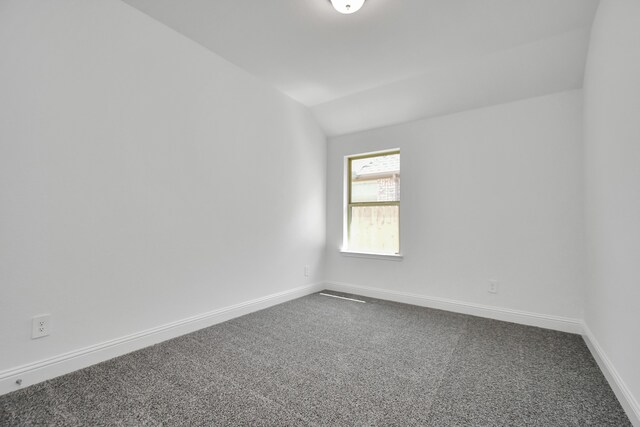 carpeted spare room with lofted ceiling