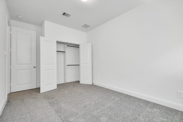 unfurnished bedroom featuring light carpet and a closet