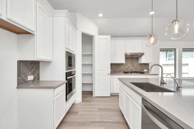 kitchen with pendant lighting, sink, white cabinetry, appliances with stainless steel finishes, and light hardwood / wood-style floors