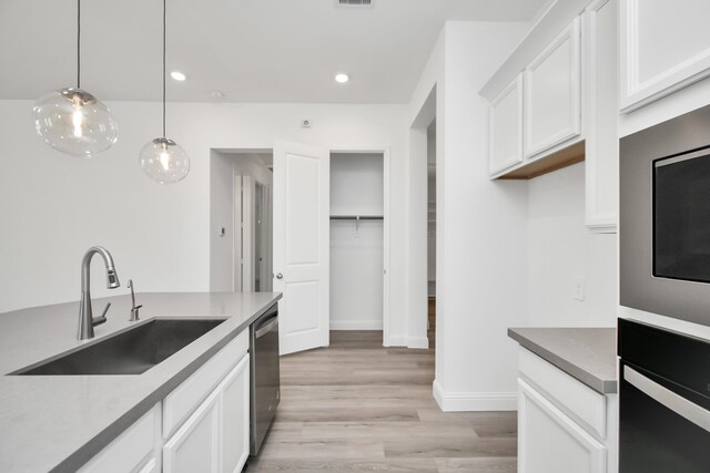 kitchen with light hardwood / wood-style floors, sink, white cabinetry, stainless steel appliances, and decorative light fixtures