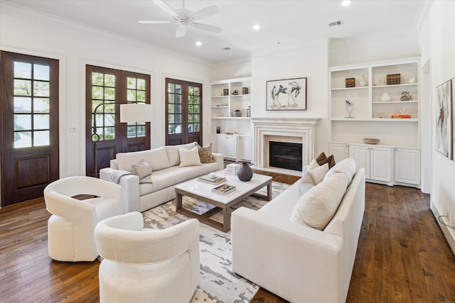 living room featuring crown molding, built in features, dark hardwood / wood-style floors, and ceiling fan