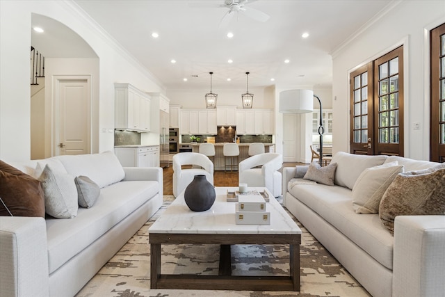 living room with ornamental molding, light hardwood / wood-style floors, and ceiling fan