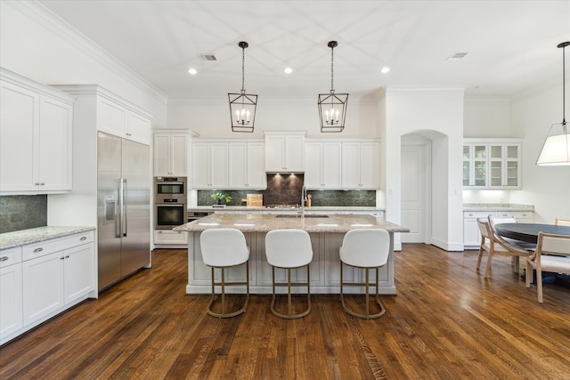 kitchen with appliances with stainless steel finishes, decorative light fixtures, dark hardwood / wood-style floors, and white cabinets