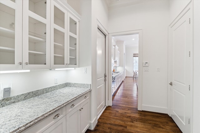 bar featuring dark wood-type flooring, white cabinetry, and light stone counters