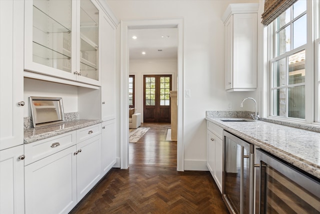 kitchen featuring white cabinets, light stone counters, sink, and beverage cooler