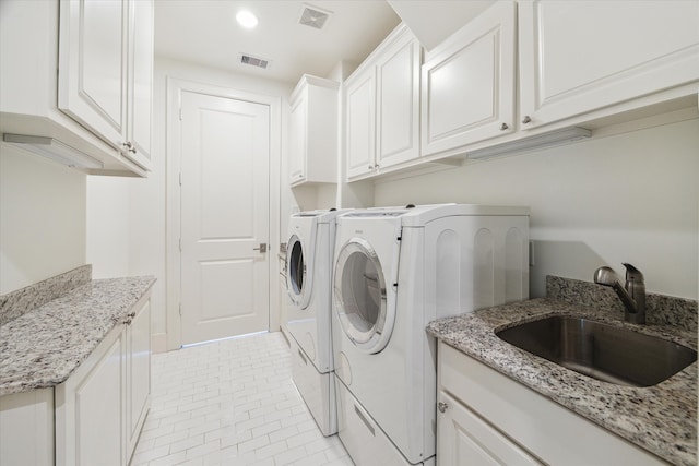 clothes washing area with light tile patterned floors, cabinets, sink, and washer and clothes dryer