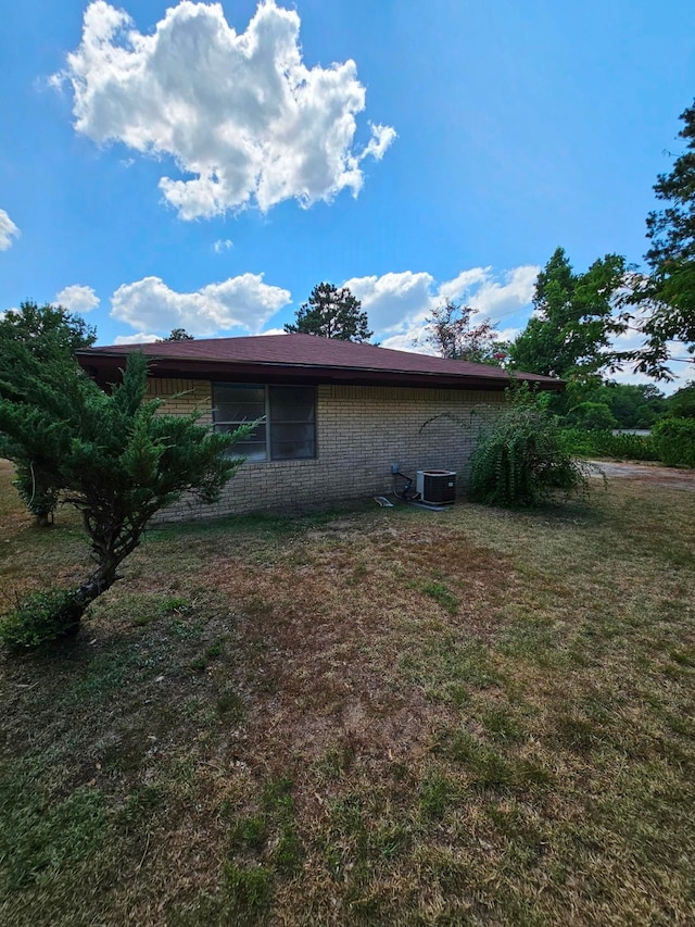 view of side of home featuring a lawn and central AC