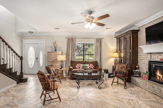 living room with a textured ceiling, ceiling fan, ornamental molding, and a fireplace