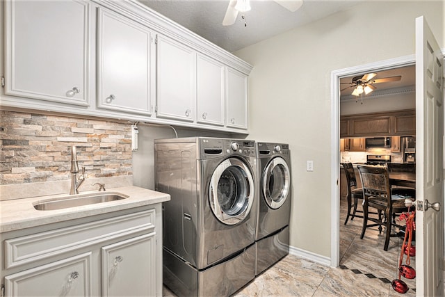 clothes washing area with ceiling fan, sink, cabinets, a textured ceiling, and washer and dryer