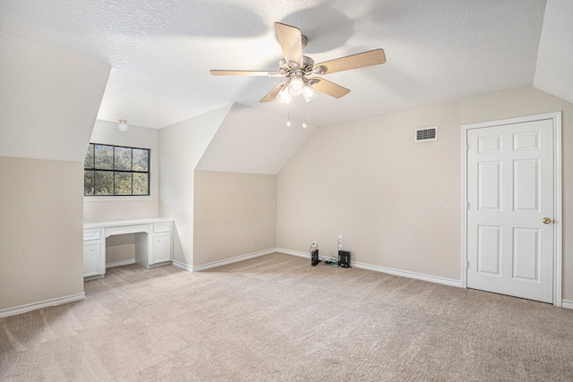 additional living space featuring a textured ceiling, ceiling fan, light carpet, and vaulted ceiling