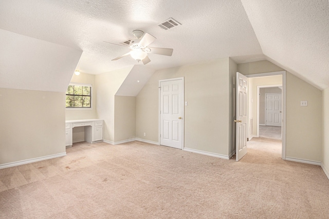 additional living space featuring a textured ceiling, ceiling fan, light colored carpet, and vaulted ceiling