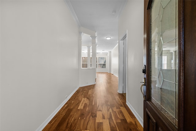 corridor with hardwood / wood-style floors, ornate columns, a wealth of natural light, and ornamental molding