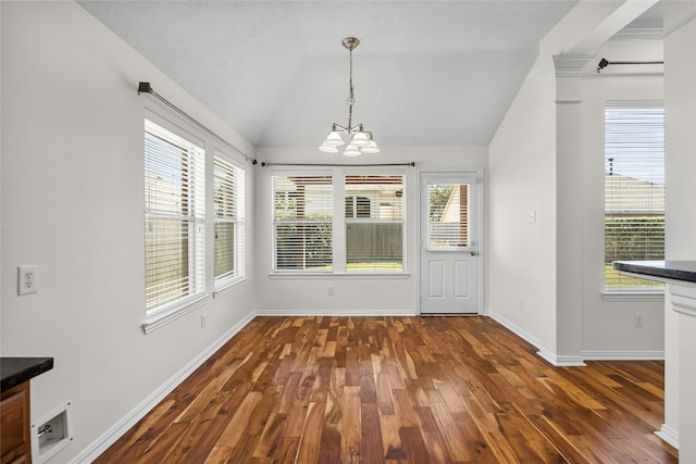 unfurnished dining area with dark wood-type flooring, a healthy amount of sunlight, lofted ceiling, and an inviting chandelier