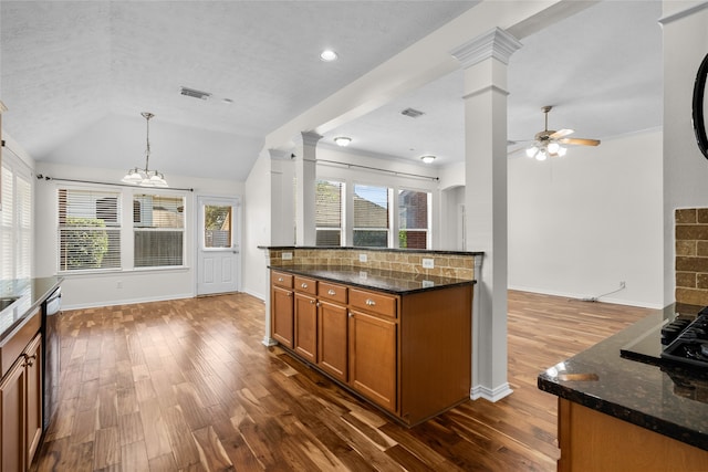 kitchen with ceiling fan with notable chandelier, dark hardwood / wood-style flooring, dark stone countertops, and hanging light fixtures