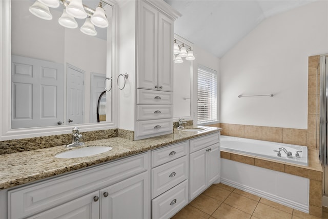 bathroom with tile patterned flooring, vanity, a tub to relax in, and vaulted ceiling