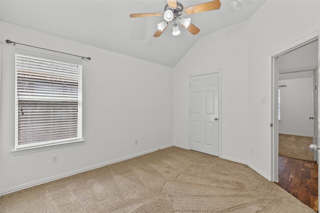 carpeted spare room featuring ceiling fan and vaulted ceiling