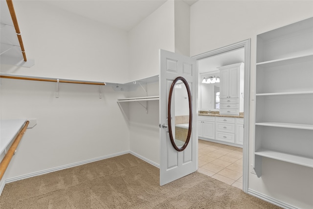 walk in closet with sink and light colored carpet