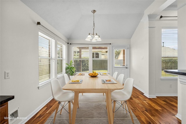 dining room featuring dark hardwood / wood-style flooring, an inviting chandelier, and vaulted ceiling