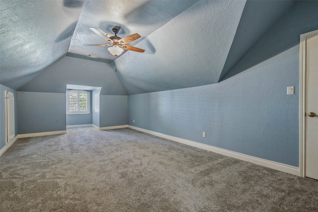 additional living space featuring carpet, a textured ceiling, vaulted ceiling, and ceiling fan