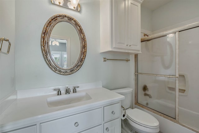 full bathroom with combined bath / shower with glass door, vanity, and toilet