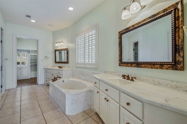 bathroom with tiled tub, vanity, tile patterned floors, and a wealth of natural light