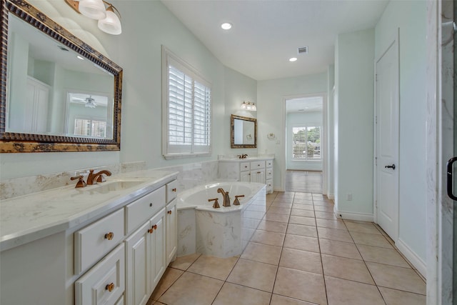 bathroom featuring a relaxing tiled tub, vanity, and a healthy amount of sunlight