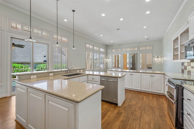 kitchen featuring hardwood / wood-style flooring, sink, white cabinets, kitchen peninsula, and appliances with stainless steel finishes