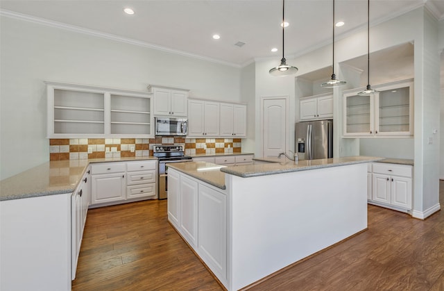 kitchen with appliances with stainless steel finishes, white cabinetry, dark hardwood / wood-style flooring, light stone countertops, and a kitchen island with sink