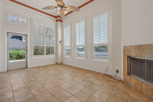 interior space featuring light tile patterned floors, ceiling fan, a fireplace, and crown molding