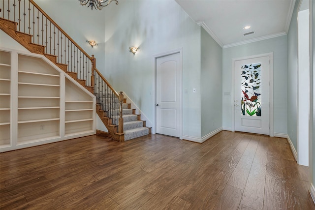 foyer featuring a notable chandelier, hardwood / wood-style flooring, ornamental molding, and a high ceiling