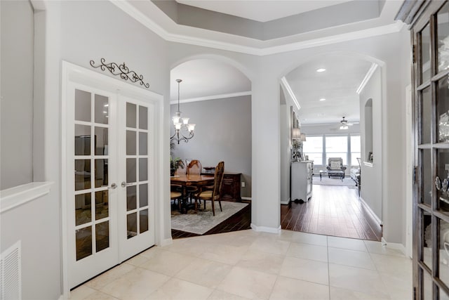 hall with french doors, crown molding, and light wood-type flooring