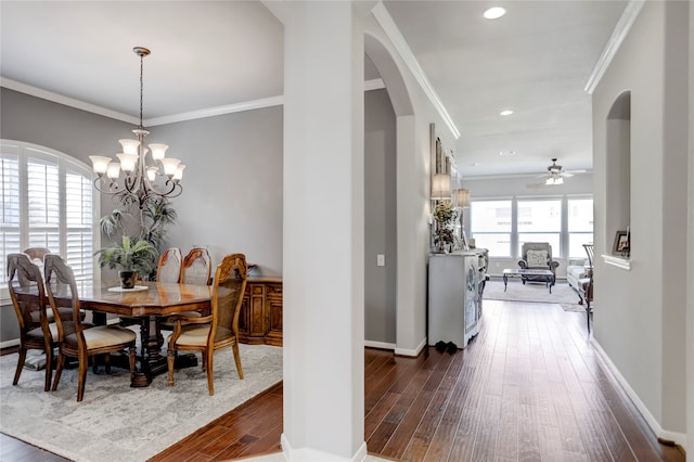 dining space with ceiling fan with notable chandelier, a healthy amount of sunlight, and dark hardwood / wood-style floors