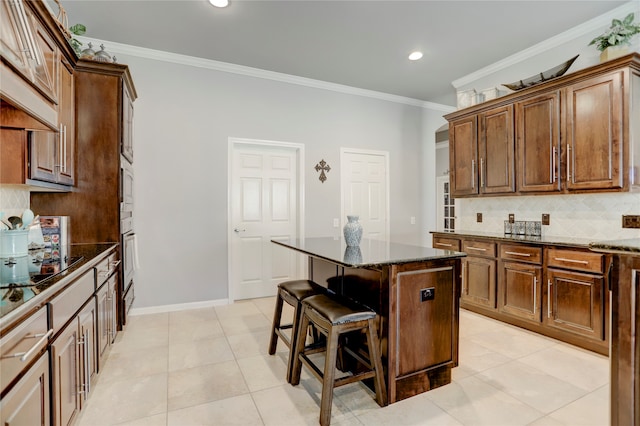 kitchen with backsplash, a kitchen island, a breakfast bar, dark stone countertops, and crown molding