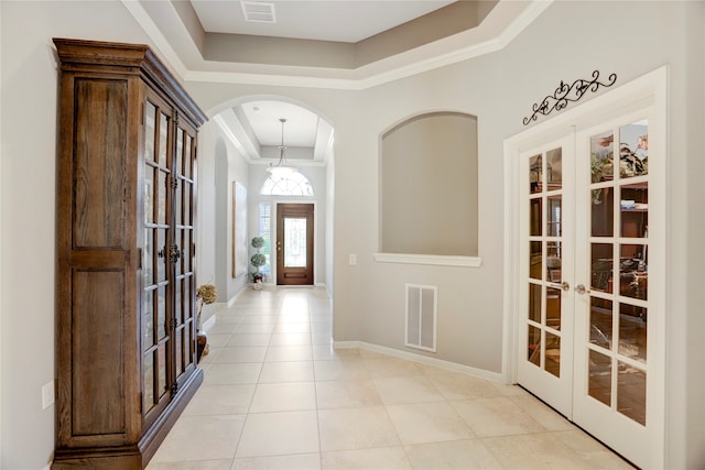 tiled foyer featuring french doors, crown molding, and a raised ceiling