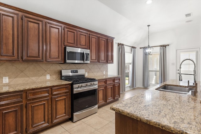 kitchen with light tile patterned floors, stainless steel appliances, decorative backsplash, decorative light fixtures, and sink