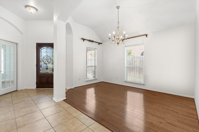 foyer featuring light hardwood / wood-style flooring, a notable chandelier, and vaulted ceiling