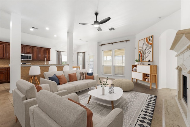 tiled living room featuring ceiling fan, a wealth of natural light, and a tile fireplace