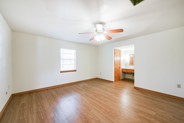 interior space with ceiling fan, light wood-type flooring, built in desk, and ensuite bathroom