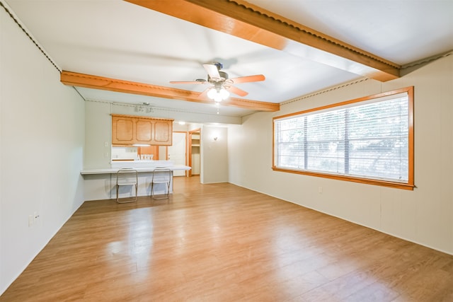 unfurnished living room with ceiling fan, light wood-type flooring, and beam ceiling