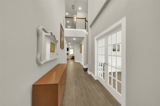 corridor with french doors, a high ceiling, and dark hardwood / wood-style floors