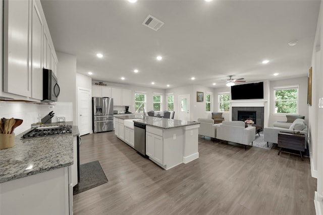 kitchen with a wealth of natural light, white cabinetry, a kitchen island with sink, and appliances with stainless steel finishes