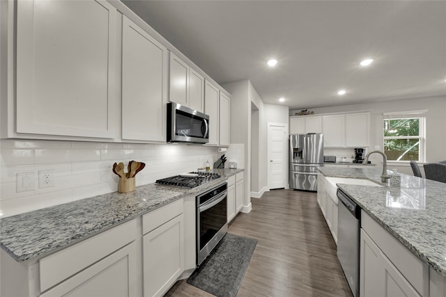 kitchen with white cabinets, sink, decorative backsplash, dark hardwood / wood-style flooring, and stainless steel appliances