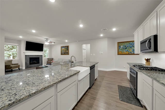 kitchen with a tile fireplace, white cabinetry, and appliances with stainless steel finishes