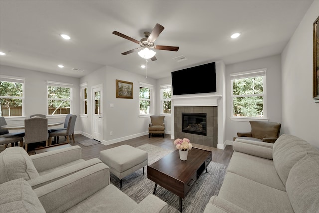 living room featuring a tile fireplace, a wealth of natural light, ceiling fan, and hardwood / wood-style flooring