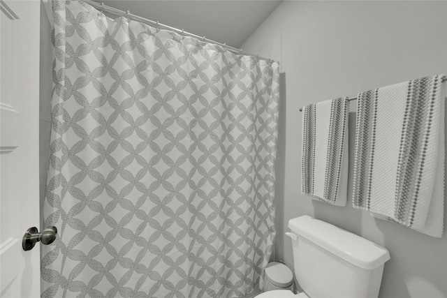 bathroom featuring toilet and curtained shower